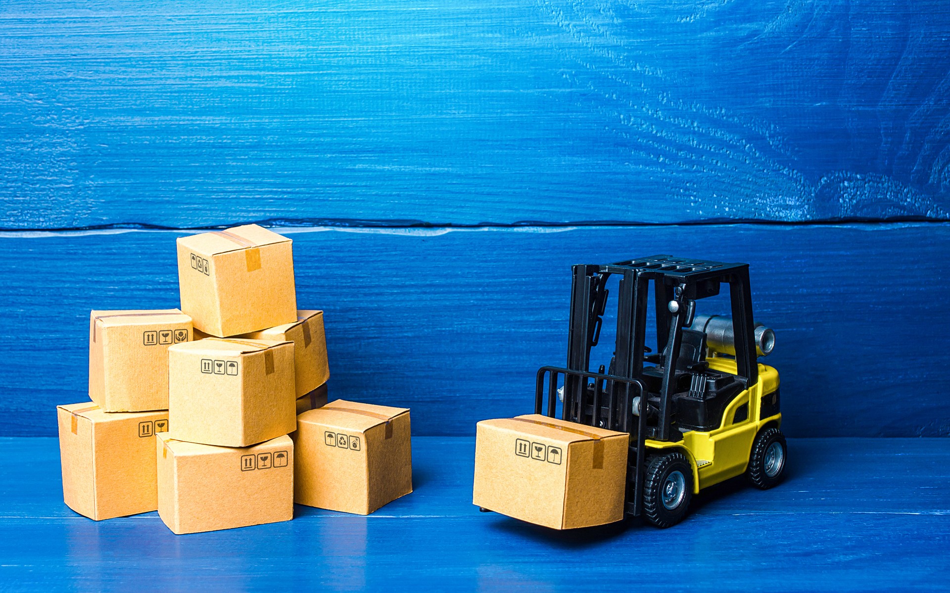 Forklift truck and cardboard boxes with goods. Logistic infrastructure and warehousing services. Transportation transfer industry. Warehouse technologies. Improving low cost efficiency delivery speed.